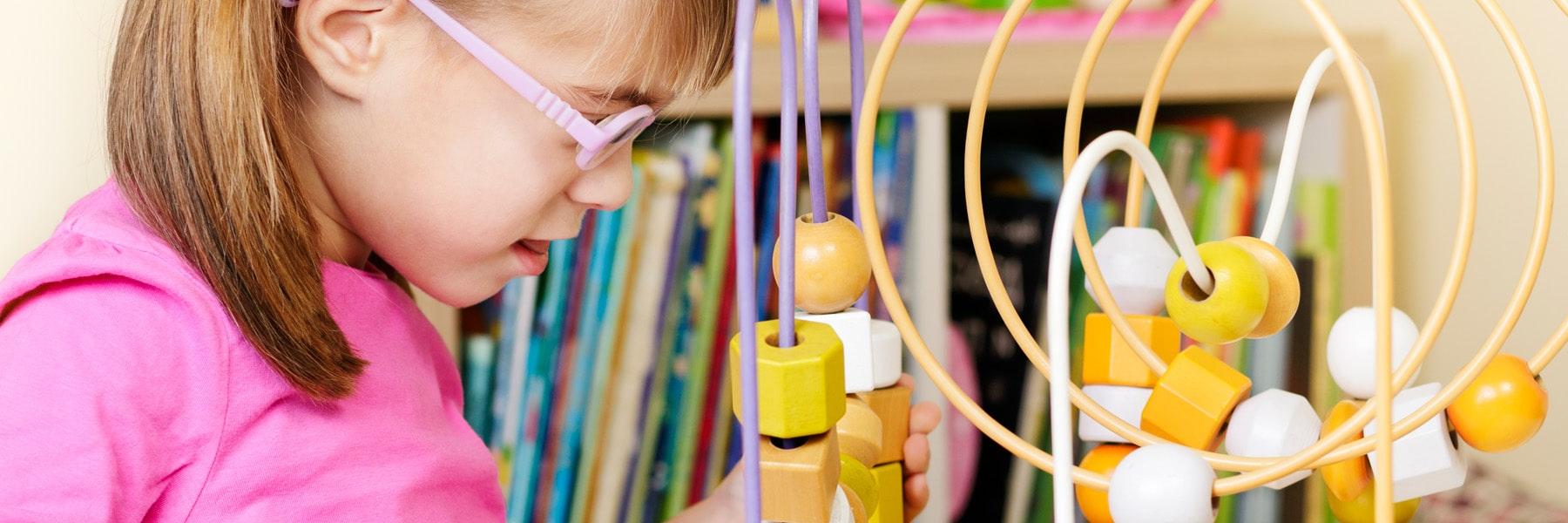 close up of toddler with pink eye glasses and circular abacus toy